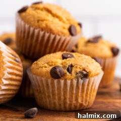 Close up of Chocolate Chip Muffins on a wooden platter, highlighting the soft interior and melted chocolate