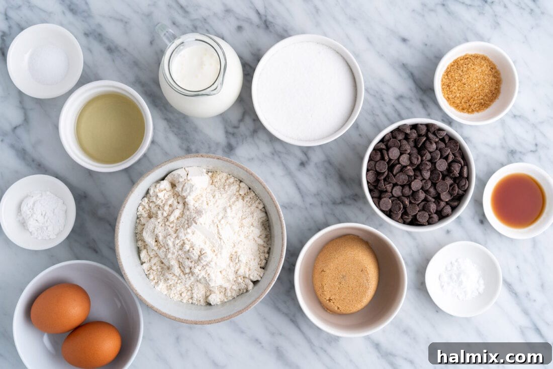 Various ingredients laid out for making chocolate chip muffins: flour, sugar, eggs, buttermilk, oil, vanilla, and chocolate chips