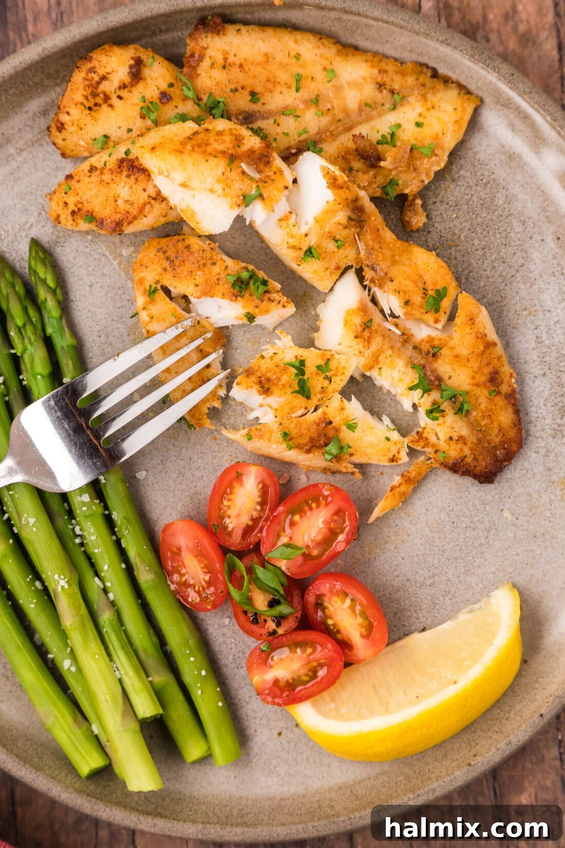 Ocean's Ancient Dweller 2 Orange Roughy broken apart on a plate with a fork, showcasing its flaky texture.