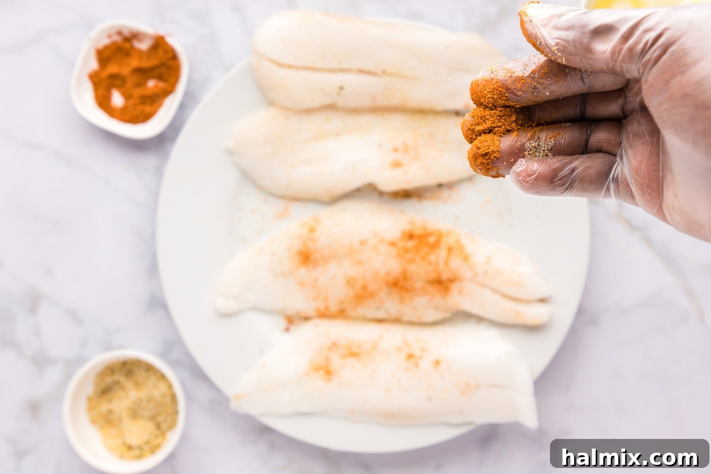 Ocean's Ancient Dweller 5 A hand rubbing a blend of garlic salt and Old Bay seasoning onto orange roughy fillets.
