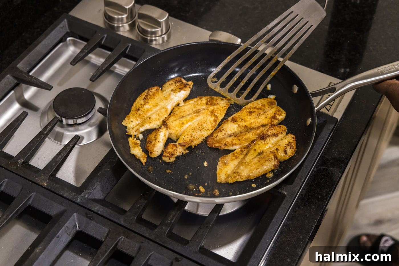 Ocean's Ancient Dweller 9 A fish turner spatula carefully flipping a pan-seared orange roughy fillet in a skillet.