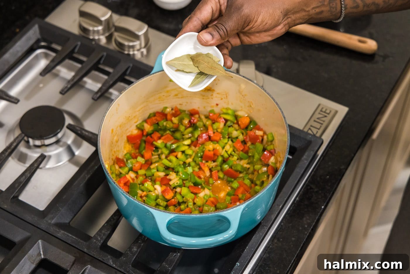 Bayou Blend 7 Four bay leaves resting on top of the sautéed vegetables in the Dutch oven, ready to be stirred in.