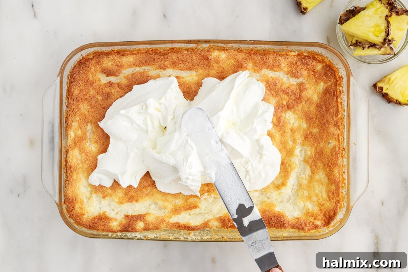 icing spatula spreading whipped cream onto angel food cake