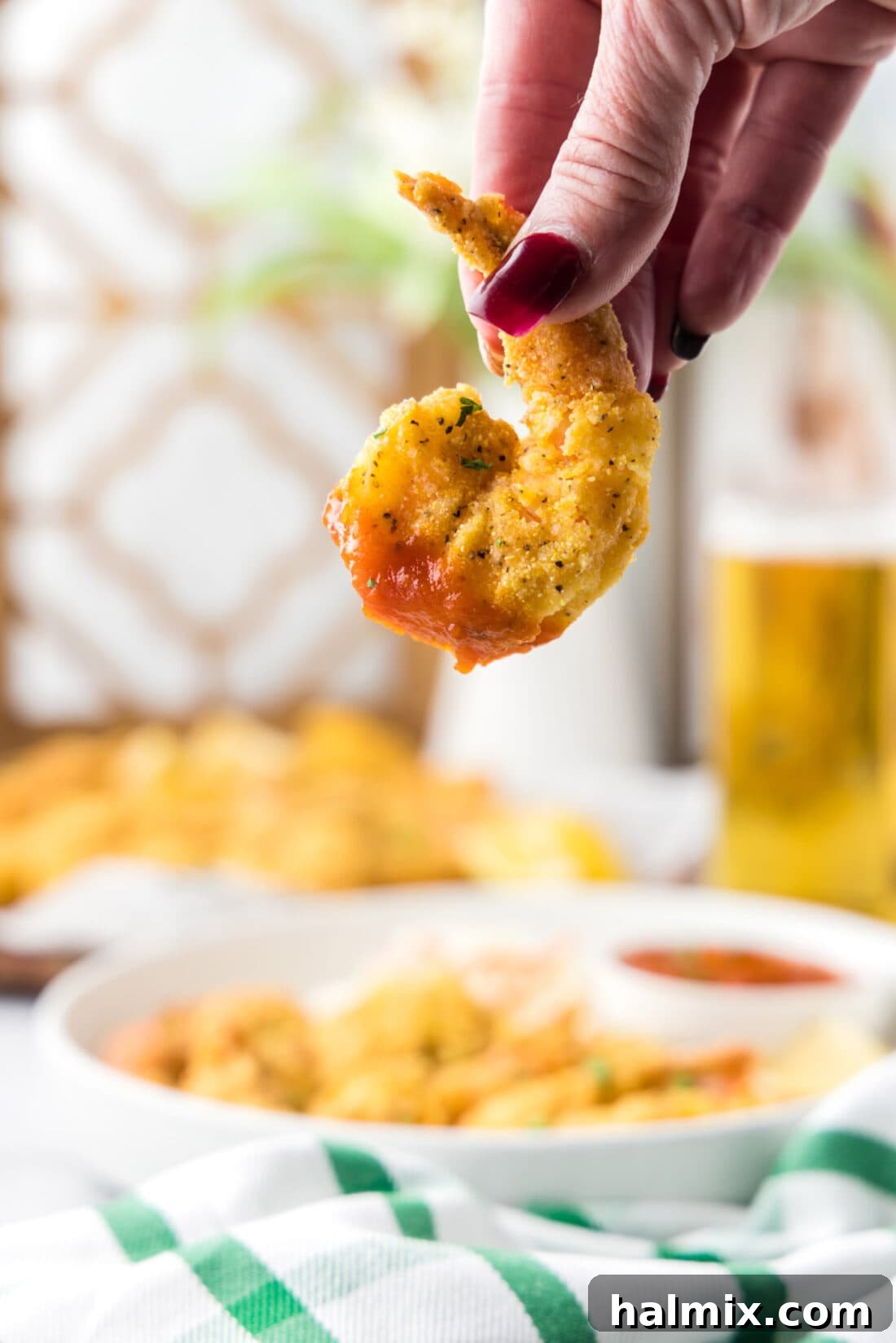 Golden Crispy Shrimp 2 A hand holding a Fried Shrimp dipped in cocktail sauce