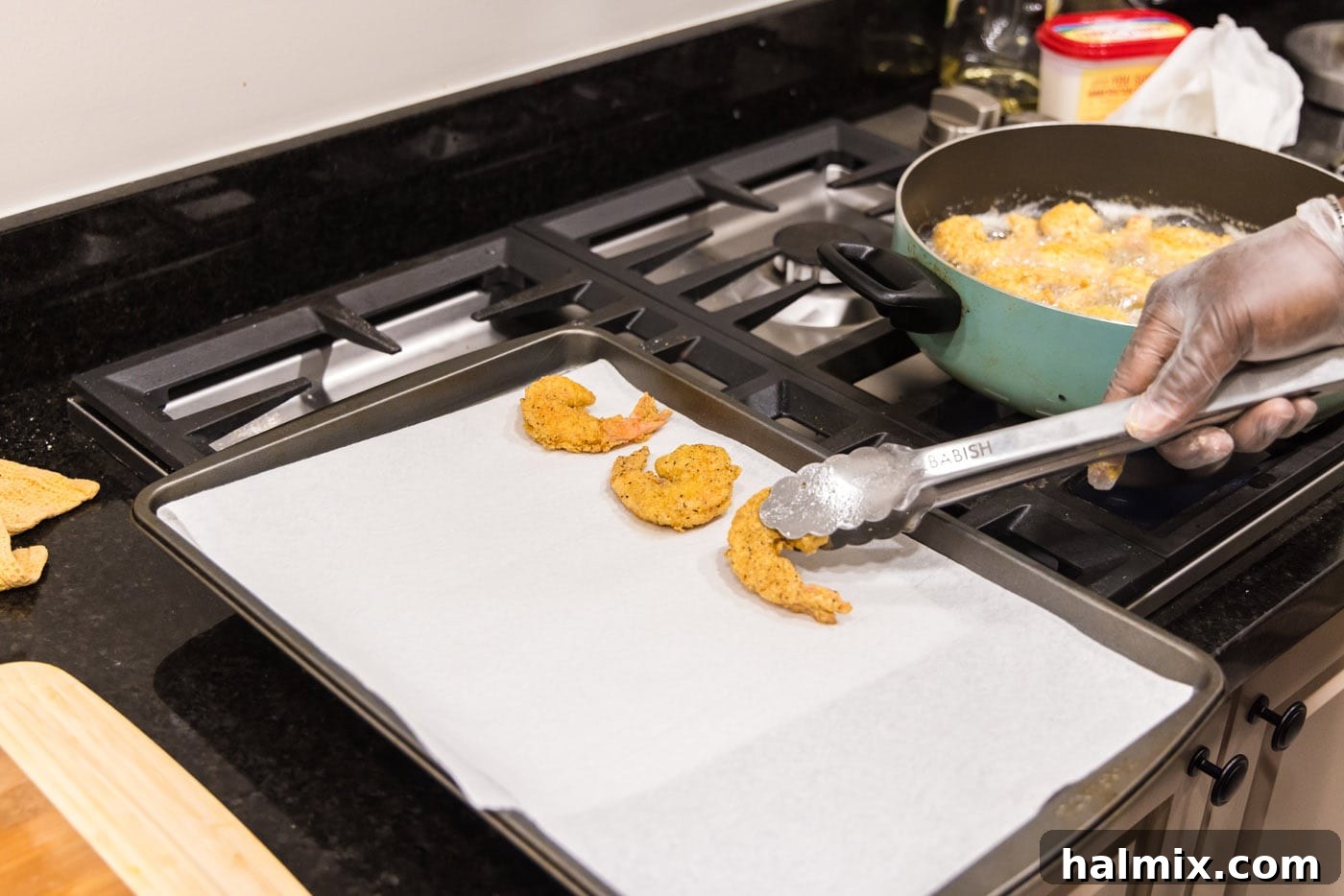 removing fried shrimp from oil and placing on paper towels