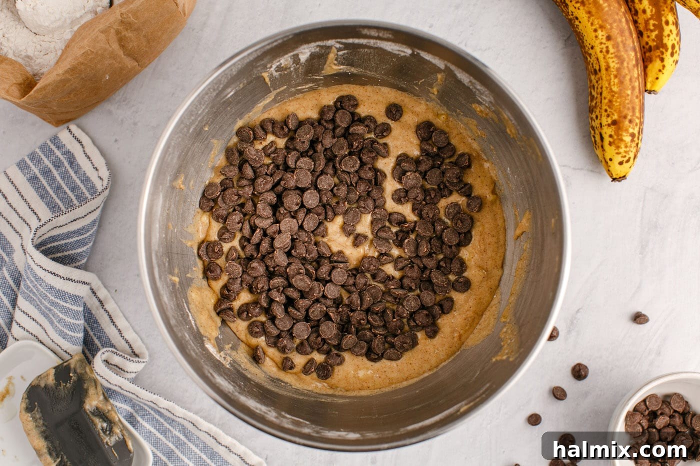 Ultimate Chocolate Chip Banana Bread 11 Chocolate chips being added to the banana bread batter in a mixing bowl.