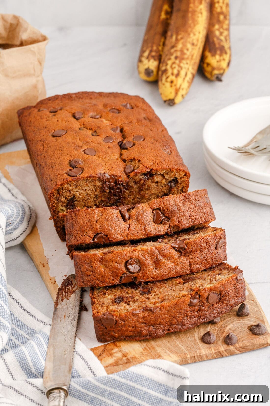 Ultimate Chocolate Chip Banana Bread 16 A beautifully sliced loaf of Chocolate Chip Banana Bread on a wooden cutting board, with individual slices ready to be served.