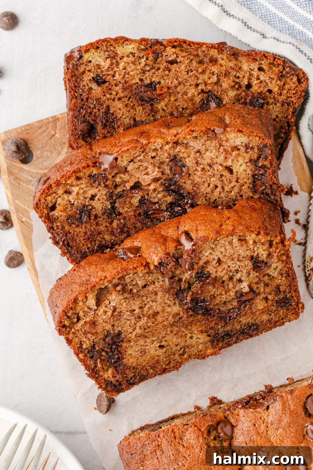 Ultimate Chocolate Chip Banana Bread 3 Three perfectly cut slices of Chocolate Chip Banana Bread revealing the moist interior and melted chocolate chips, presented on a wooden board.