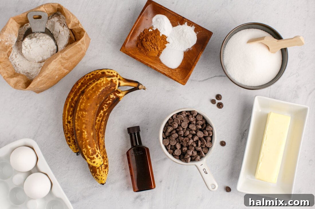 Ultimate Chocolate Chip Banana Bread 4 A collection of fresh ingredients neatly arranged on a counter, including ripe bananas, chocolate chips, flour, butter, eggs, vanilla, and spices, ready for making banana bread.