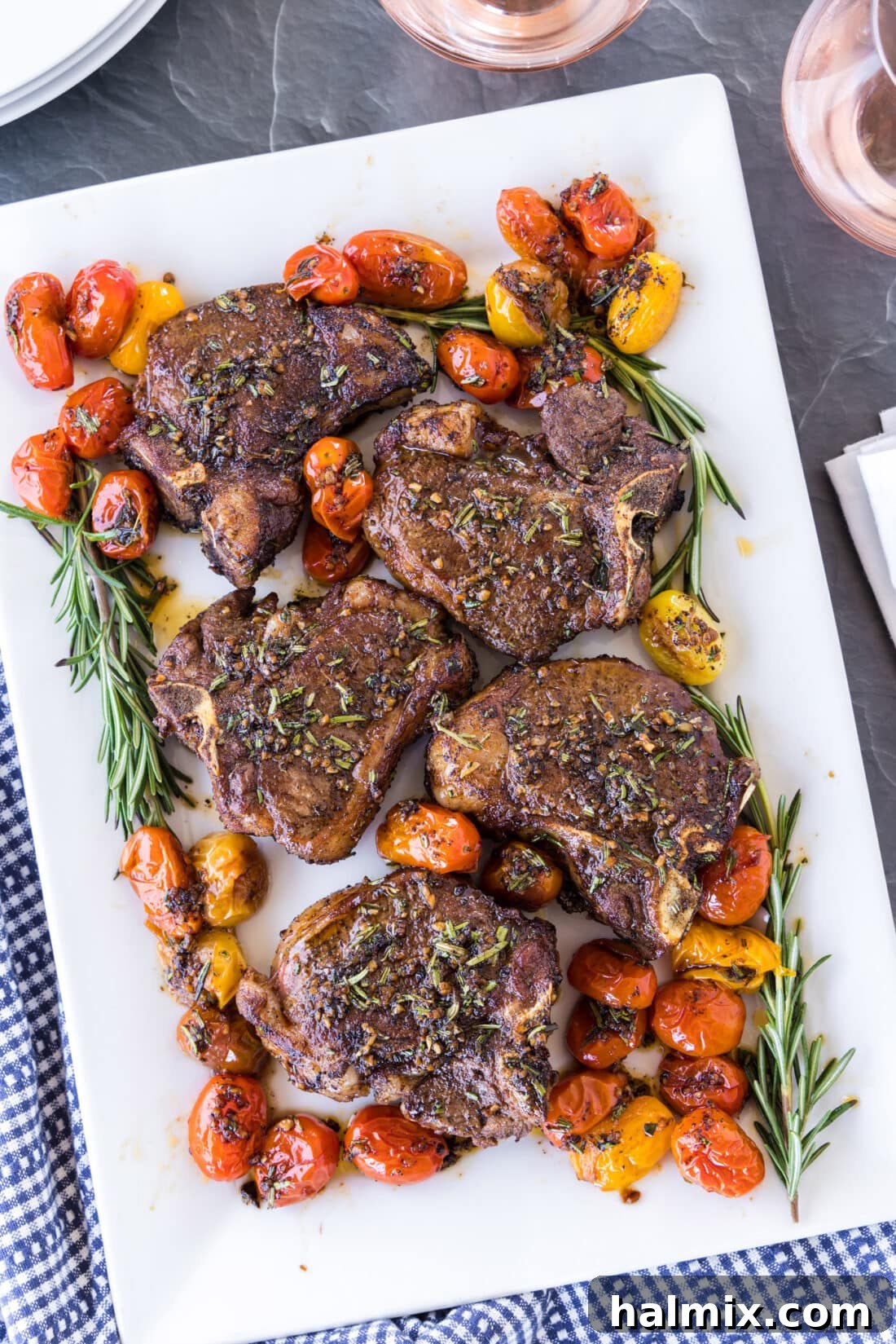 Platter of perfectly pan-seared lamb loin chops garnished with fresh rosemary sprigs
