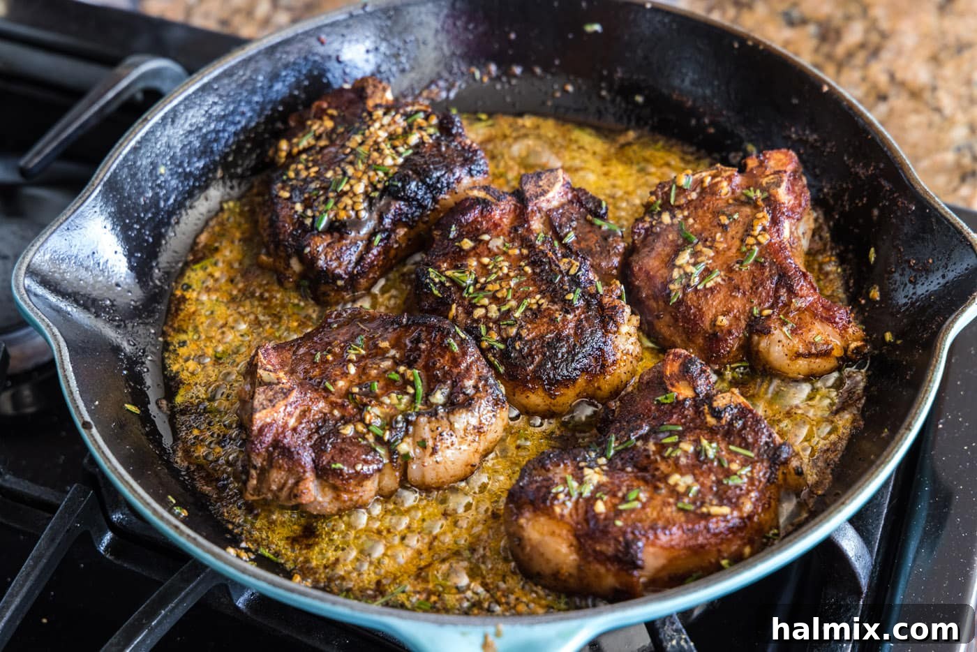 Pan seared lamb loin chops coated in butter and rosemary sauce in a skillet