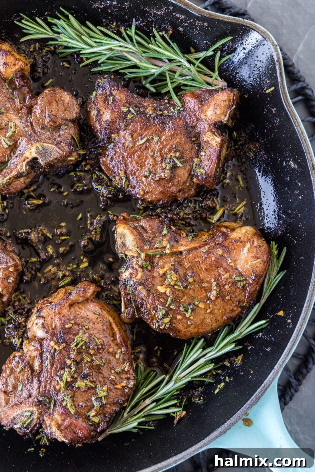Close up view of lamb loin chops sizzling in a cast iron skillet, developing a golden crust