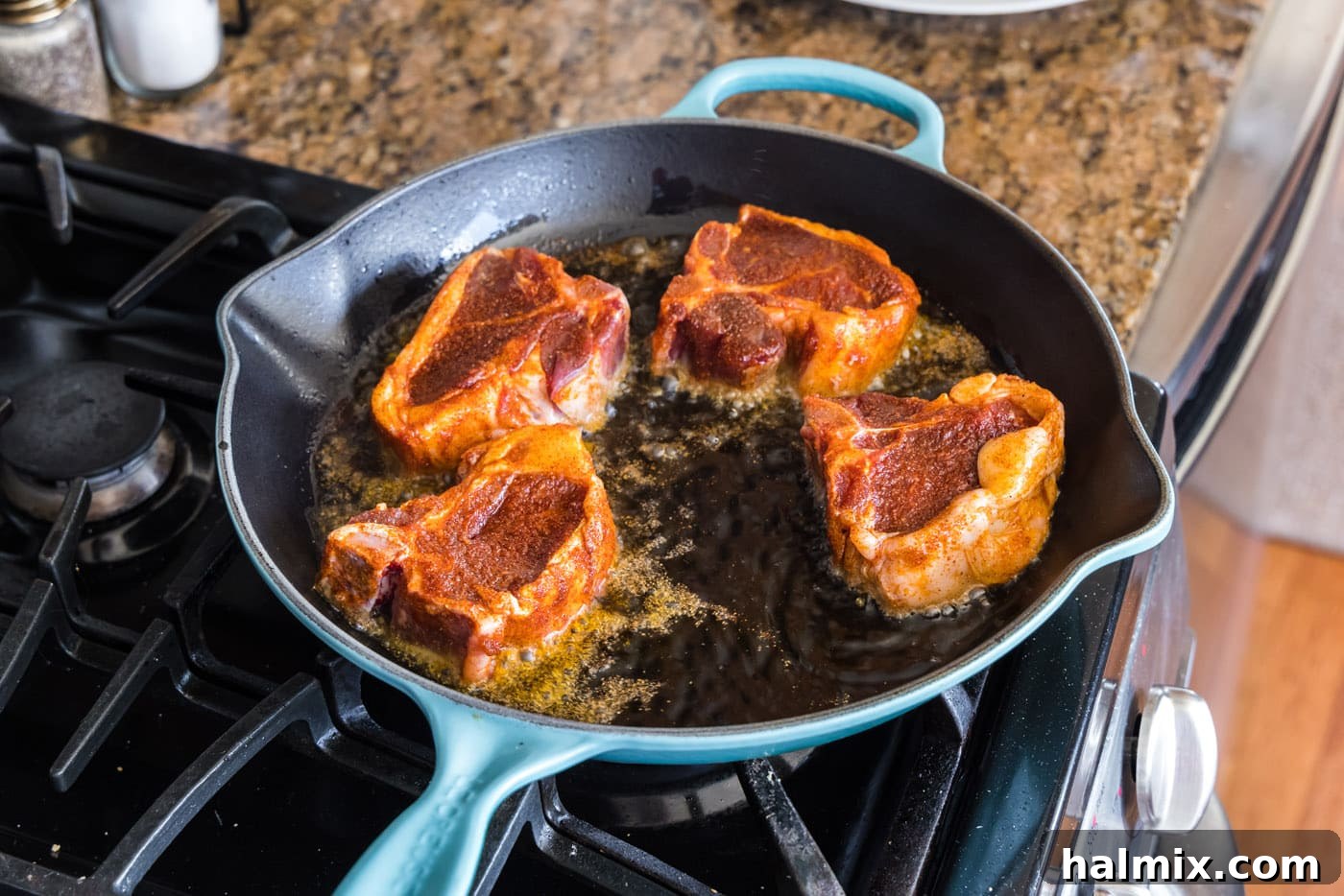 Lamb chops searing in a hot skillet, developing a brown crust
