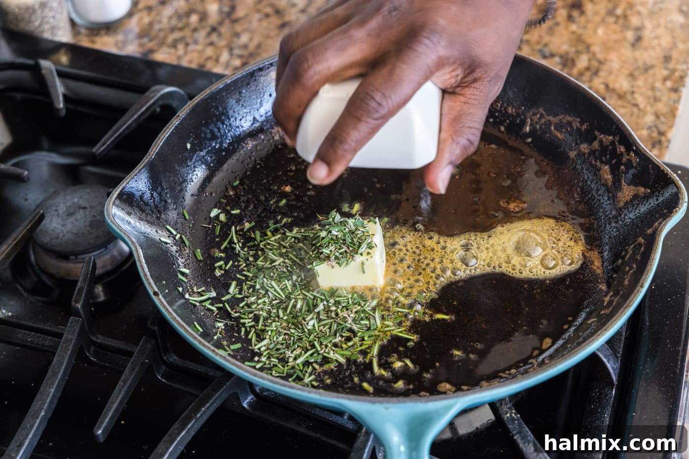 Adding butter and fresh rosemary to a skillet with pan drippings
