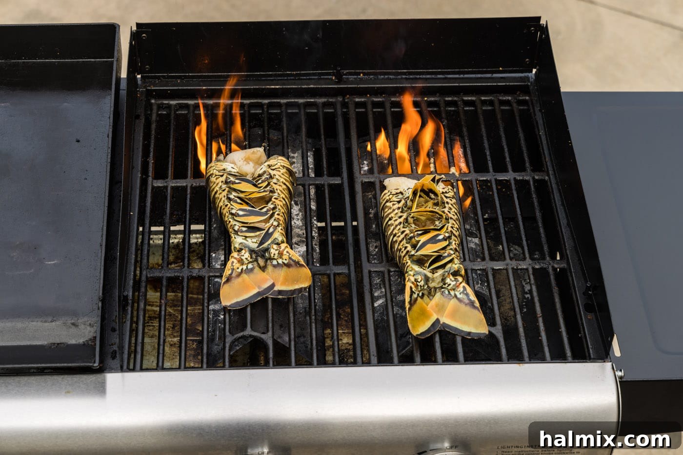 Lobster tails cooking meat-side down on a hot grill, showing the searing process.