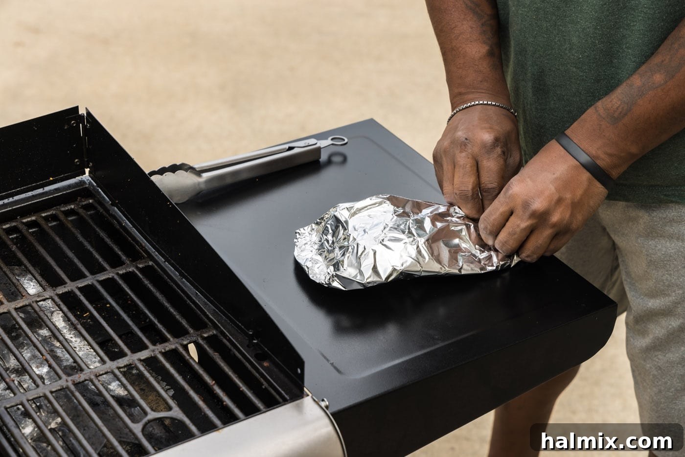 Another view of a lobster tail being carefully wrapped in aluminum foil for resting.