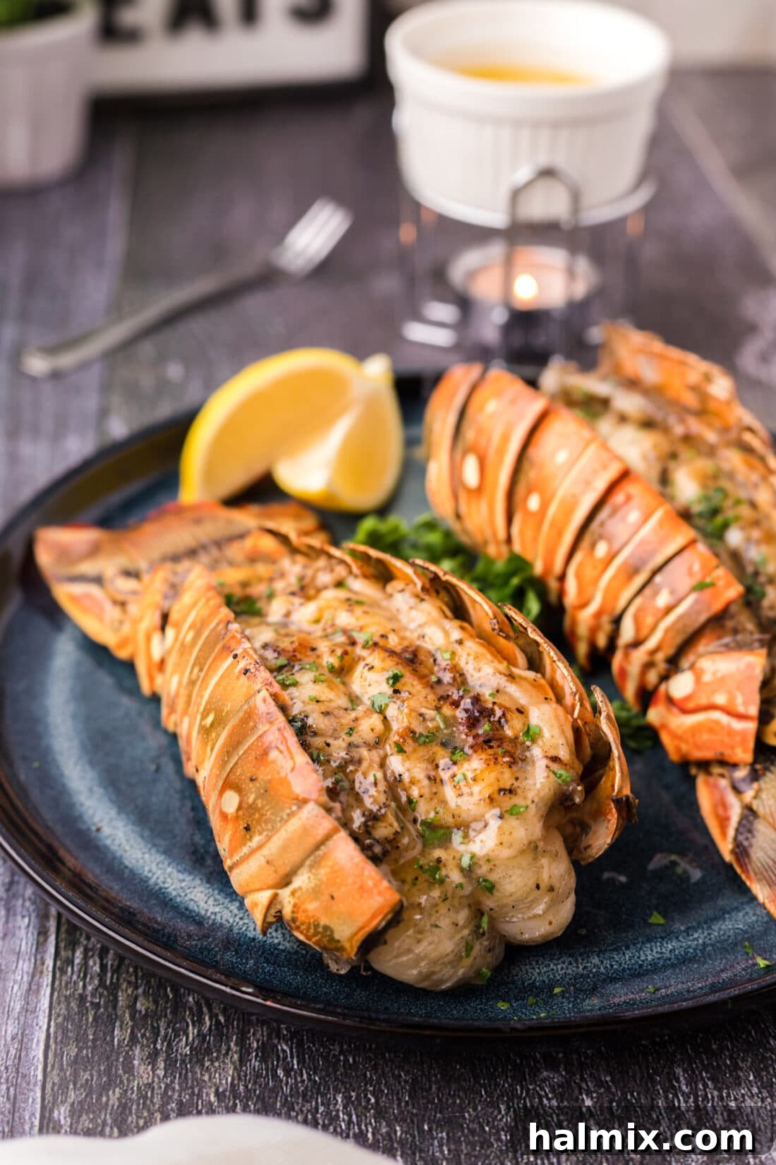 A close-up view of a succulent grilled lobster tail, garnished with fresh herbs and lemon, on a plate.