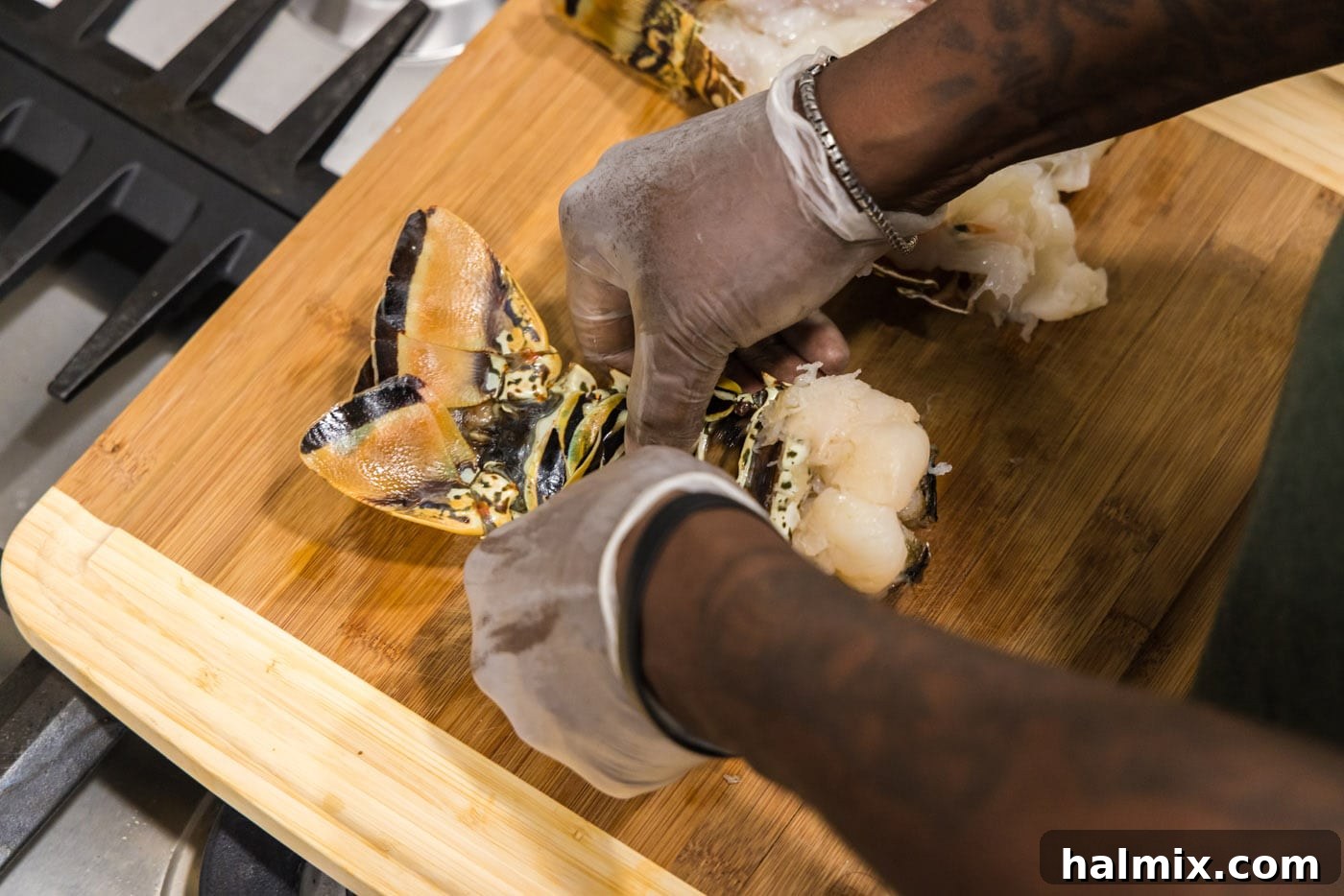 Hands carefully cracking the underbelly of a lobster shell to loosen the meat.