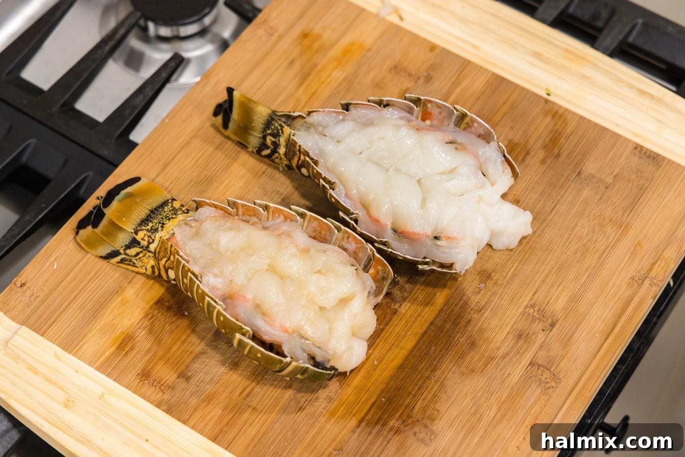 A perfectly butterflied lobster tail resting on a cutting board, meat exposed and ready for preparation.