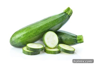Low Carb Vegetables: Your Essential Guide to What to Eat and What to Skip 10 Fresh green zucchini with a slice cut off, isolated on a white background.