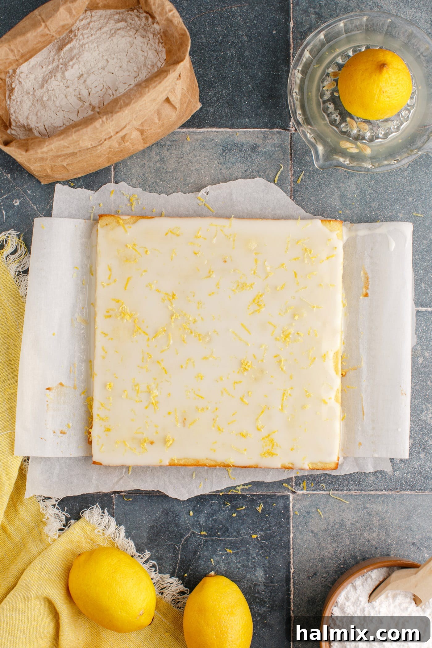 Overhead view of lemon glazed brownies garnished with fresh lemon zest, ready to be cut.