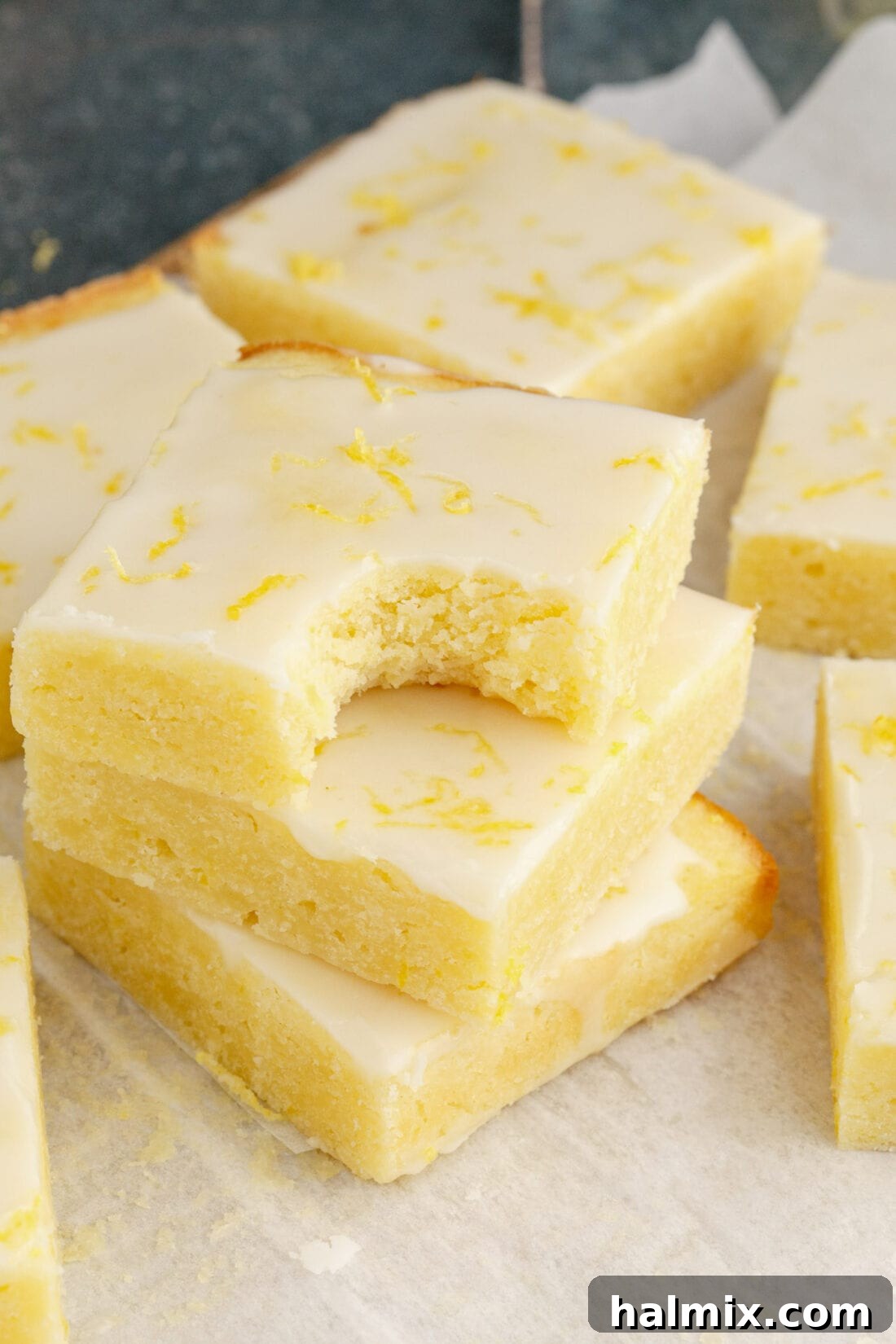Stack of Lemon Brownies with a bite taken out of the top brownie, revealing the fudgy interior.