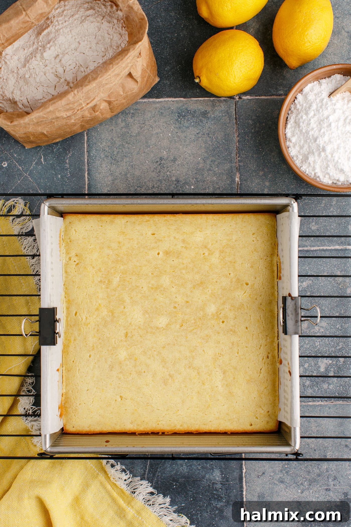 Freshly baked lemon brownies cooling in an 8x8 pan on a wire rack.