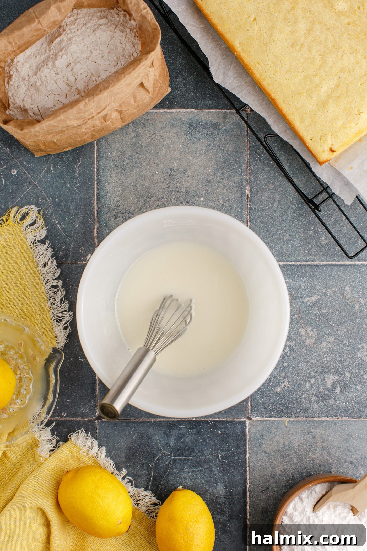 Easy lemon glaze in a small mixing bowl with a whisk, showing its smooth consistency.