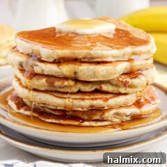 Stack of freshly made banana pancakes with a pat of butter melting on top and golden syrup drizzled over