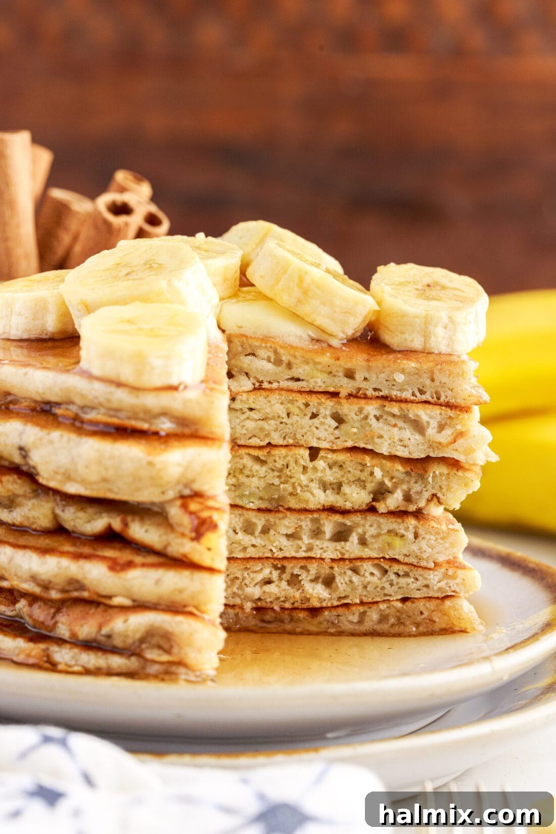 A stack of fluffy banana pancakes with a perfect slice cut out, revealing the moist, tender interior