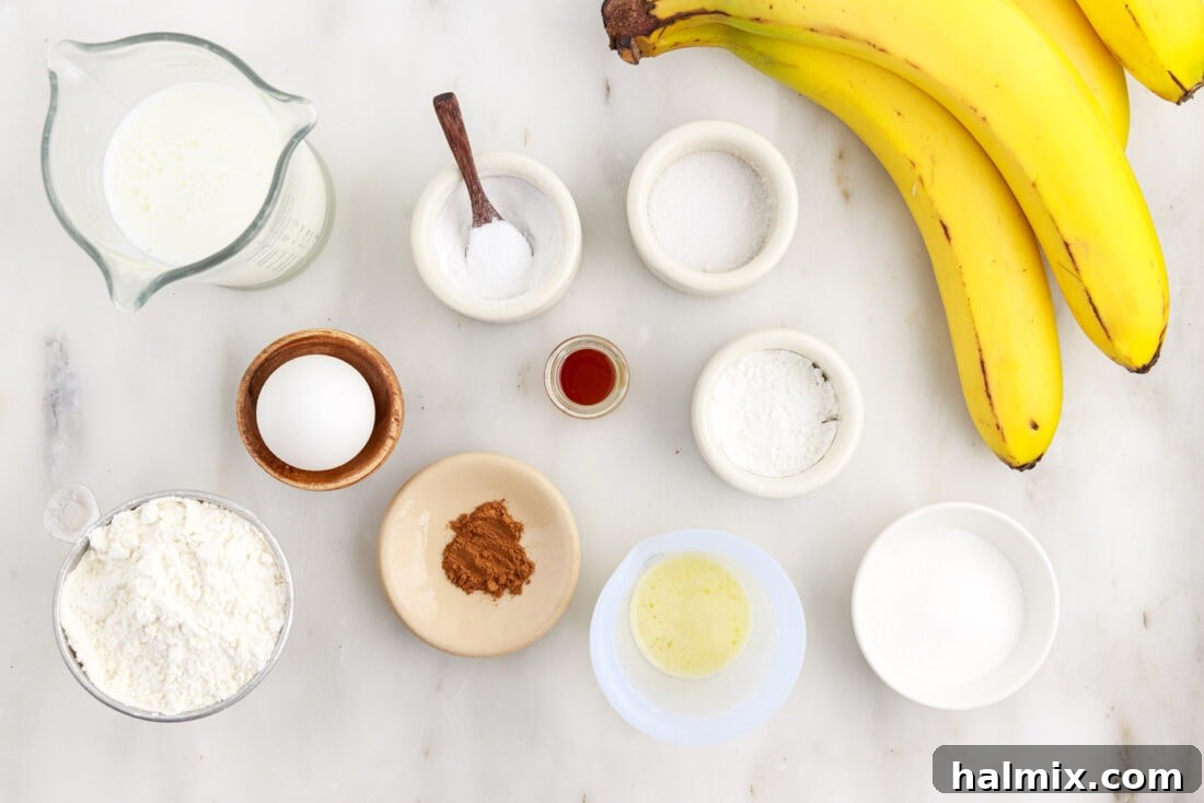 A beautiful flat lay of all the fresh ingredients for homemade banana pancakes, including ripe bananas, flour, buttermilk, egg, and spices