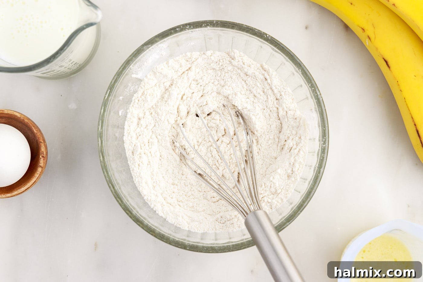 Whisking together the dry ingredients: flour, sugar, baking soda, baking powder, salt, and cinnamon in a small bowl