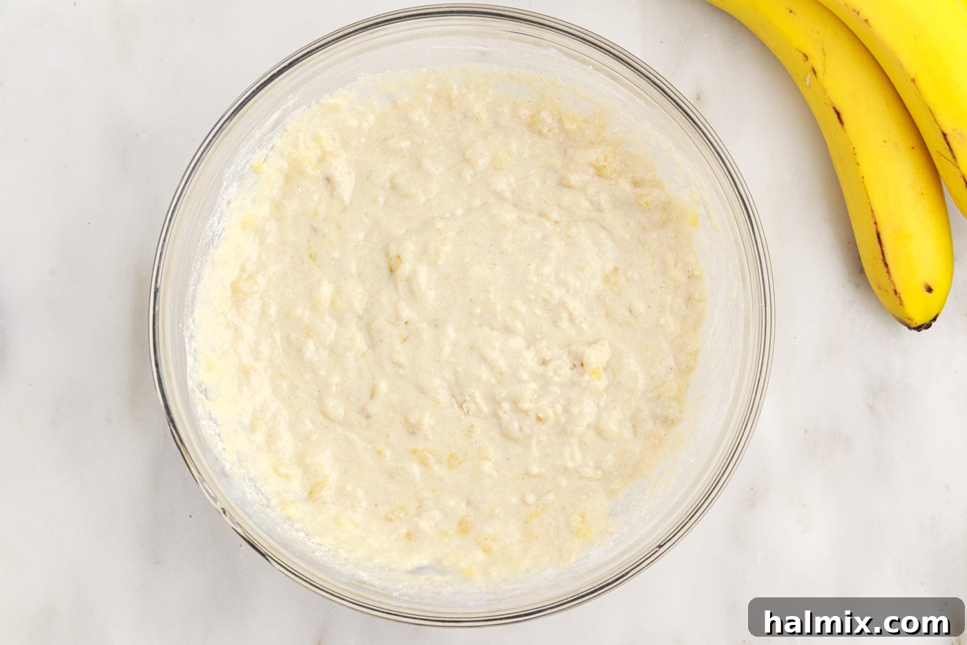 The lumpy consistency of the banana pancake batter, indicating it's perfectly mixed for fluffy results