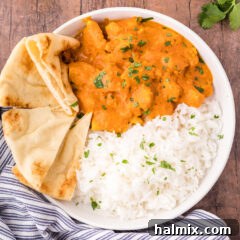 Close up of a bowl of Chicken Tikka Masala with rice and naan bread