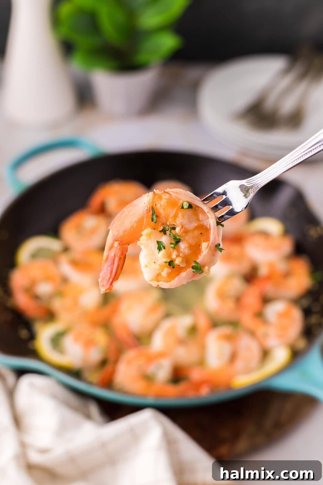 A single perfectly cooked Garlic Butter Shrimp held by a seafood fork