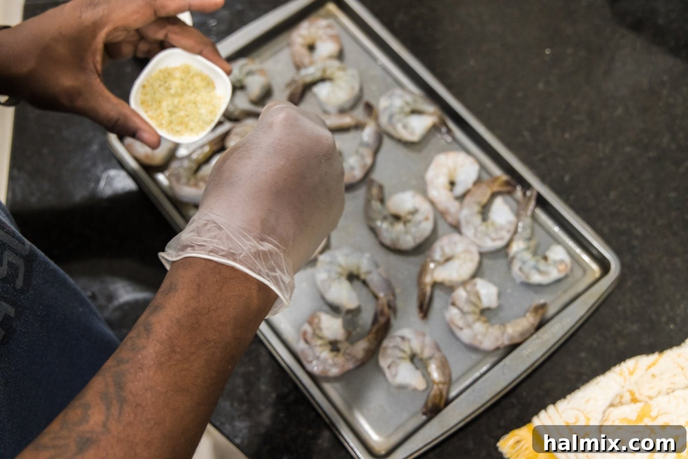 Seasoning raw shrimp on a baking sheet with garlic salt