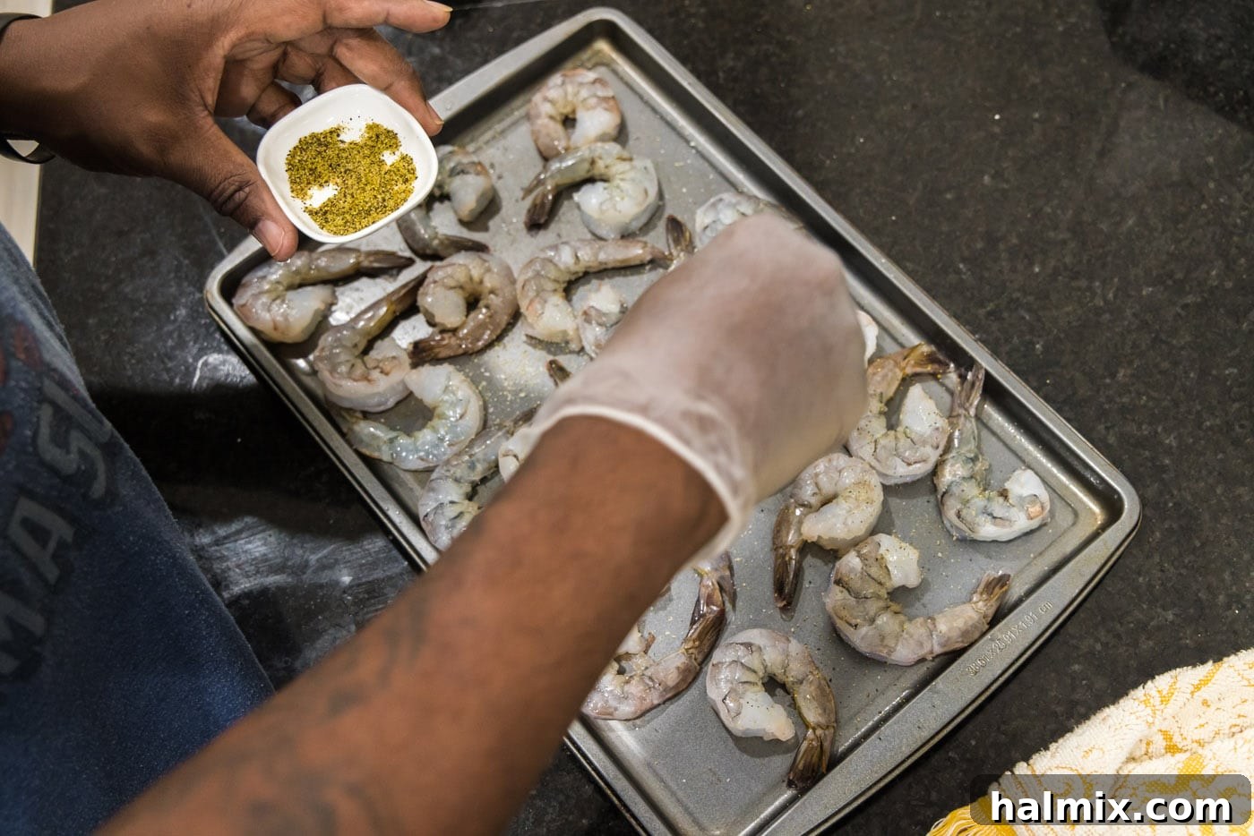 Sprinkling lemon pepper over shrimp for seasoning