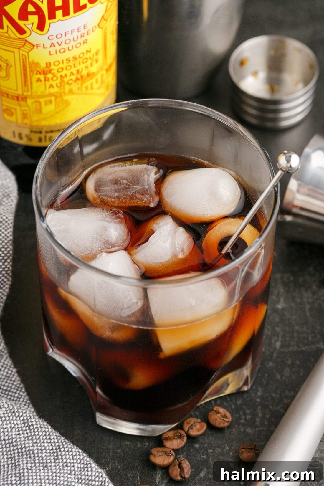 Black Russian with a Kahlua bottle in the background, showcasing the rich, dark hue of the cocktail