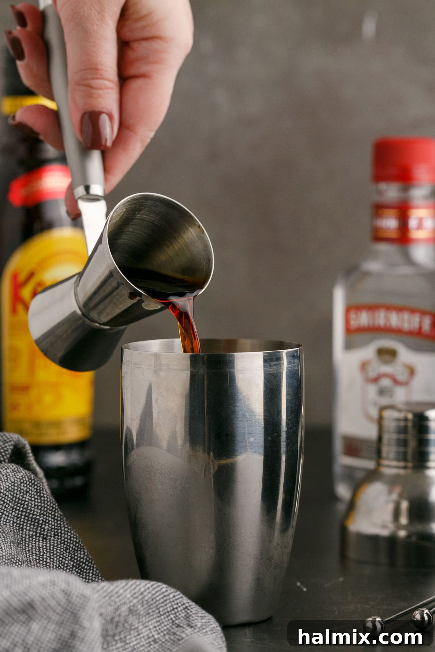 pouring Kahlua into cocktail shaker filled with ice