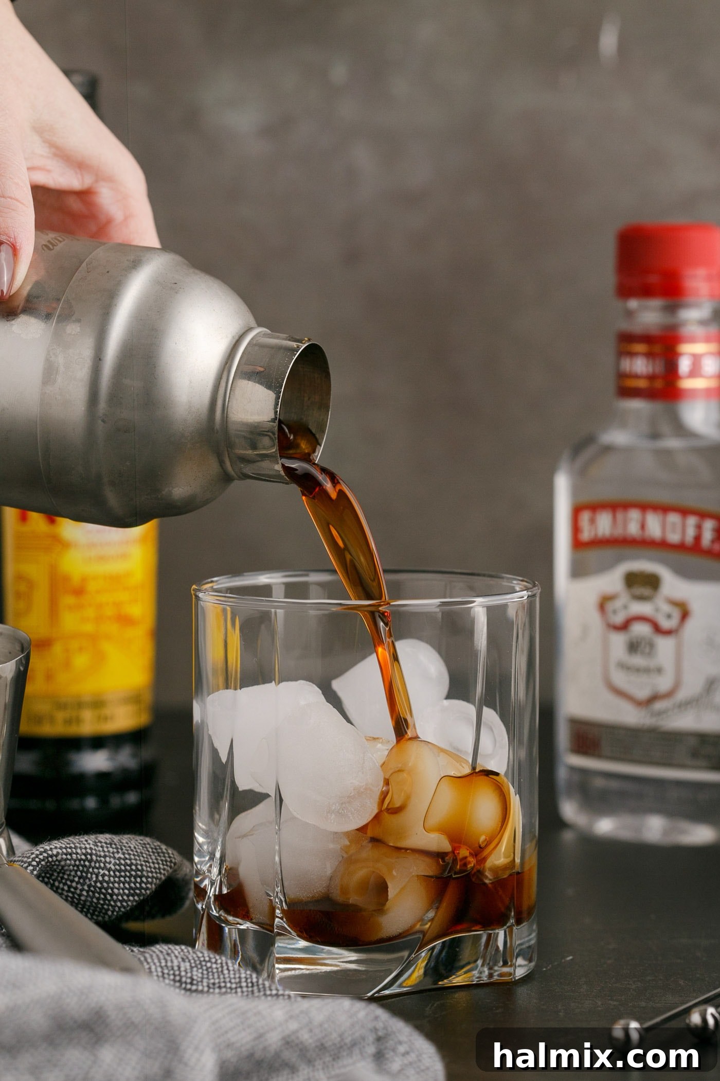 Shaken Black Russian being poured into a rocks glass with ice