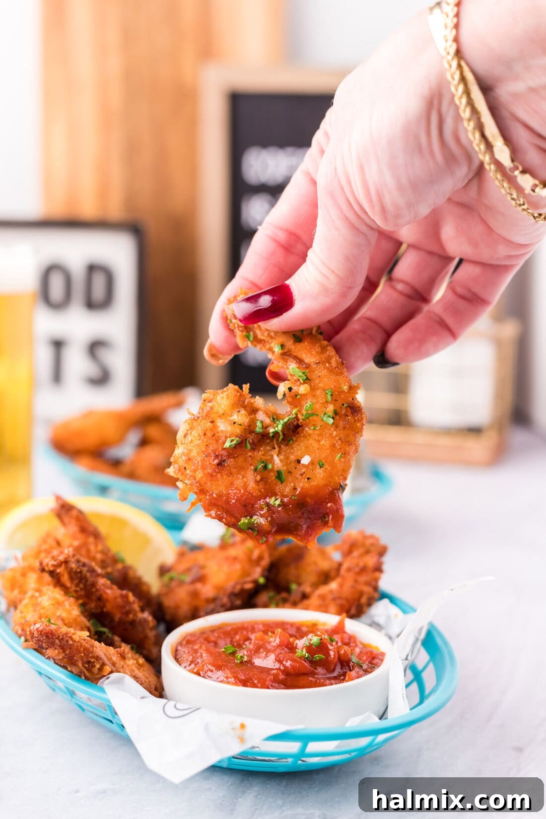 Crispy Coconut Shrimp 2 Coconut Shrimp dipped in cocktail sauce, showcasing its golden crust and plump interior