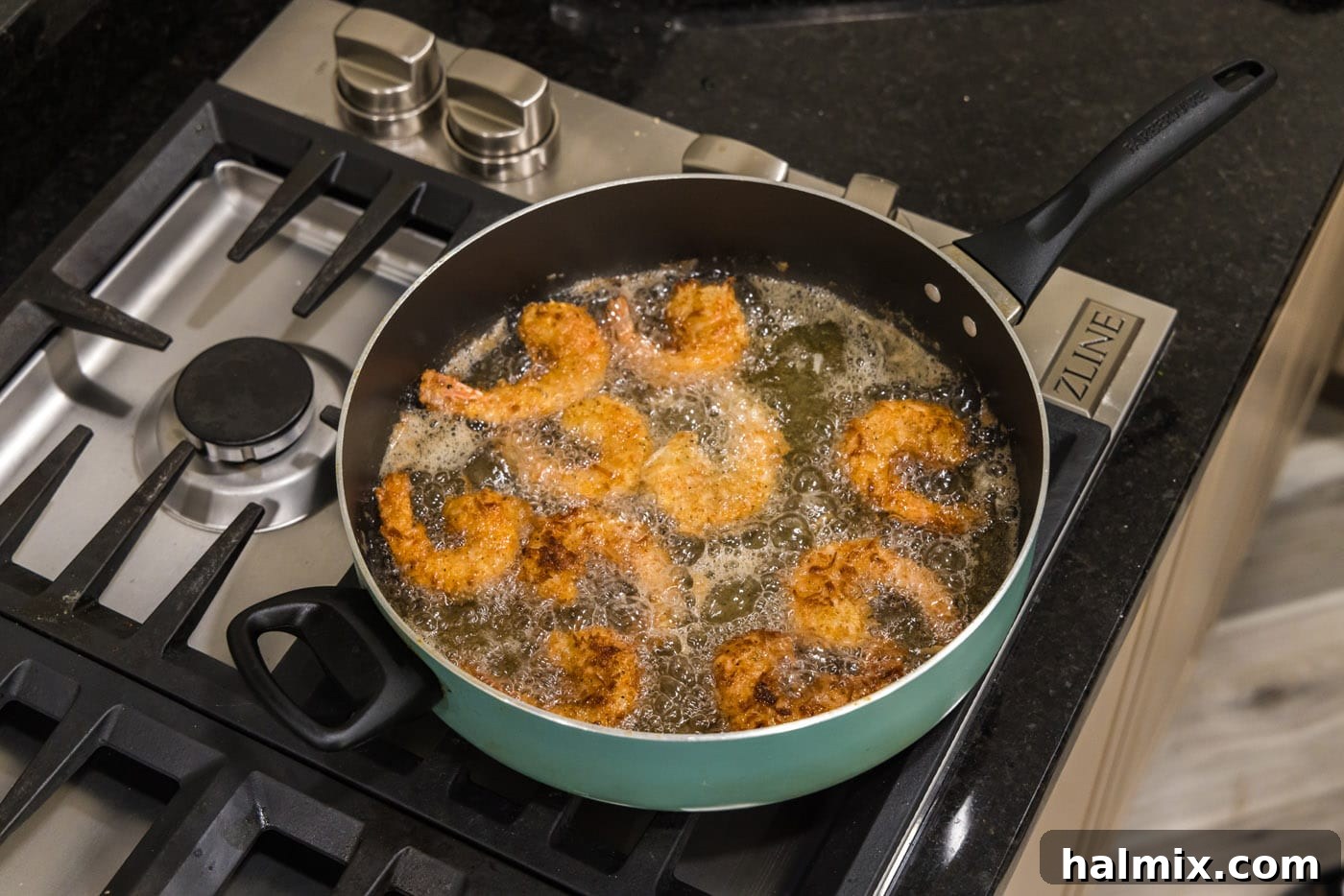 A batch of golden-brown coconut breaded shrimp sizzling in a skillet of oil