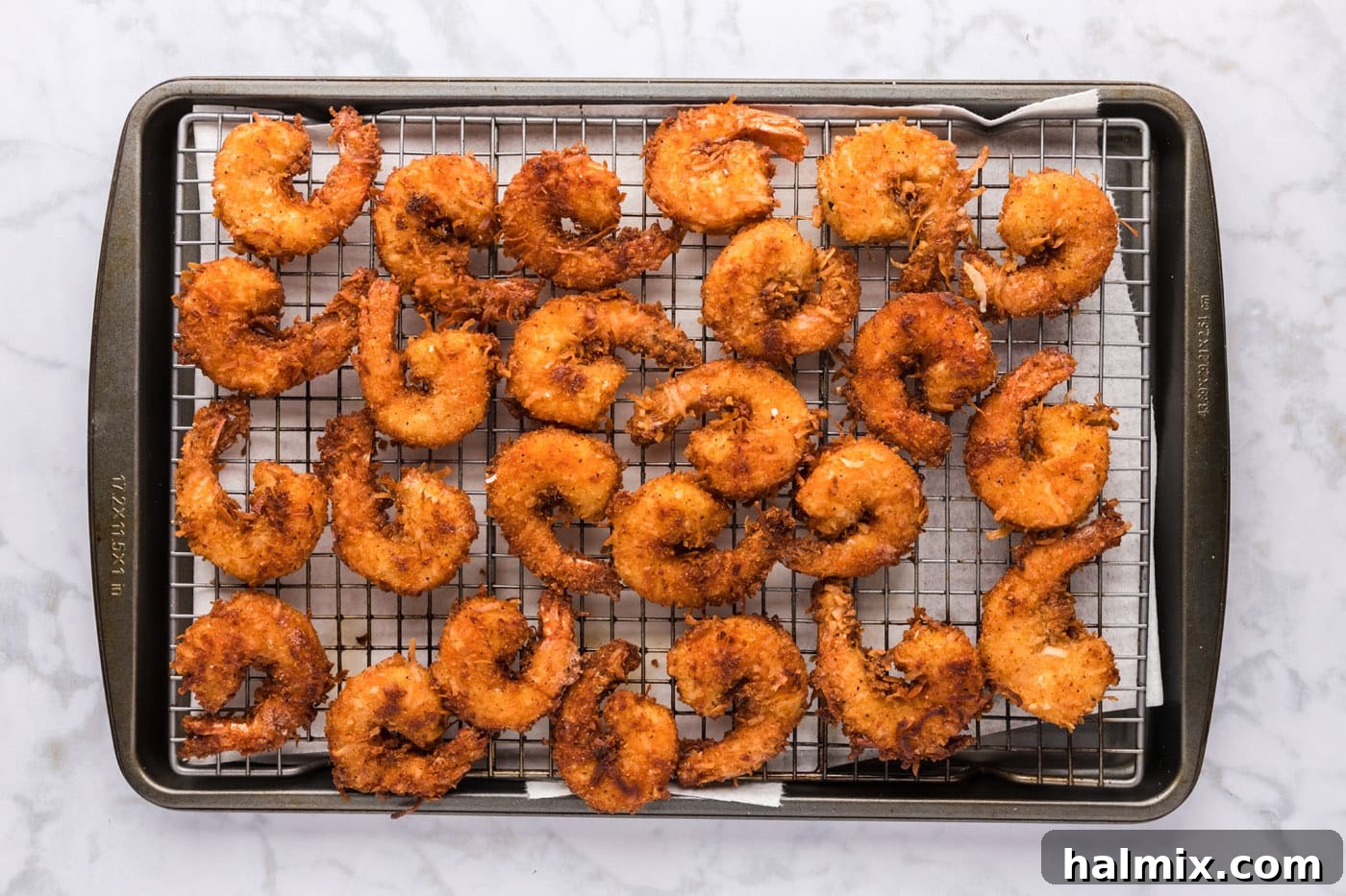 Beautifully golden coconut shrimp cooling and draining on a wire rack