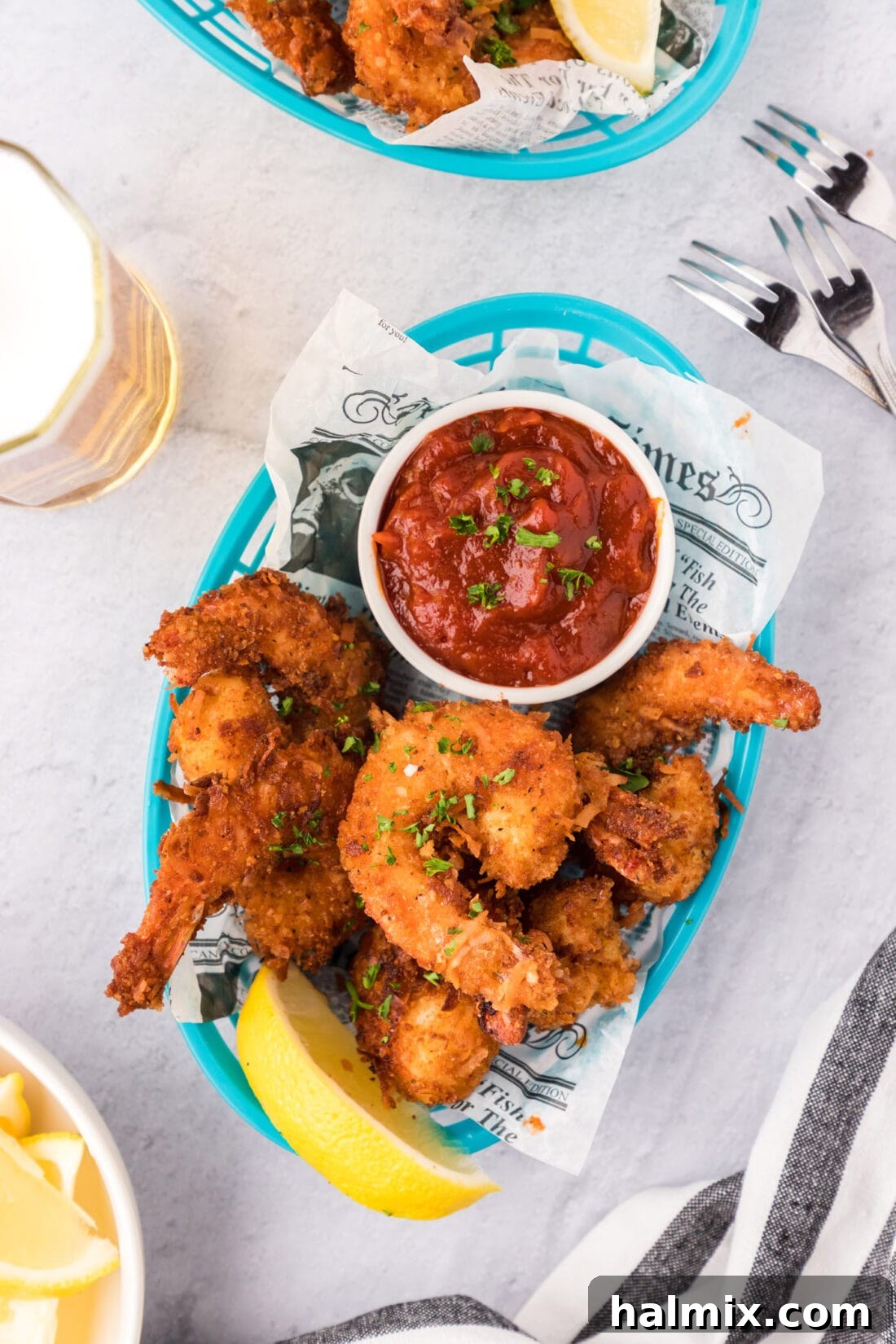 Crispy Coconut Shrimp 3 Coconut Shrimp in a basket with a bowl of cocktail sauce, ready to be served