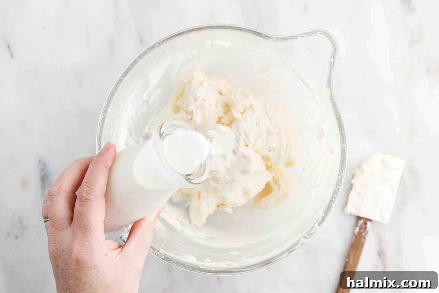 Festive Sprinkle Cake 16 adding cream to frosting in a bowl