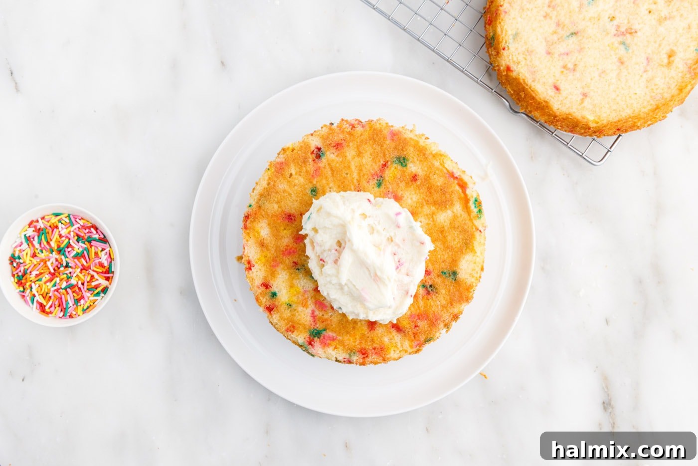 Festive Sprinkle Cake 19 frosting on top of cake laye