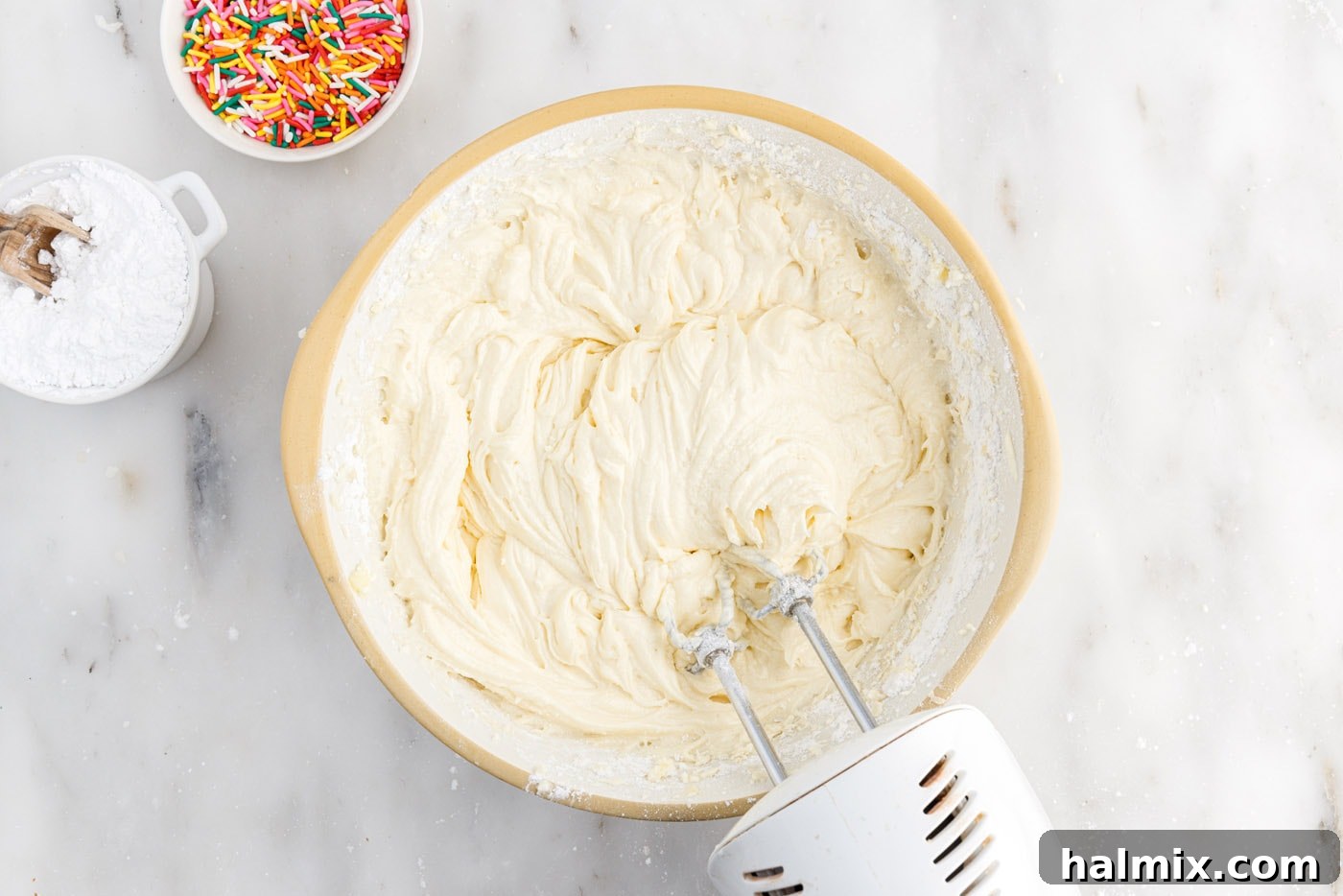 Festive Sprinkle Cake 10 beating cake batter with a hand mixer