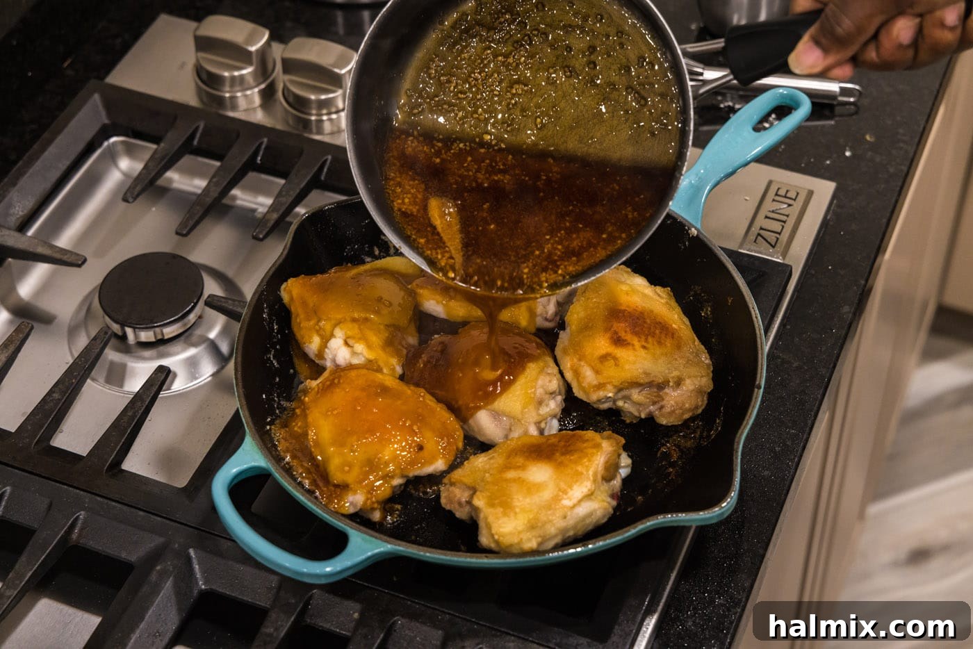 pouring honey garlic sauce over chicken thighs in a skillet
