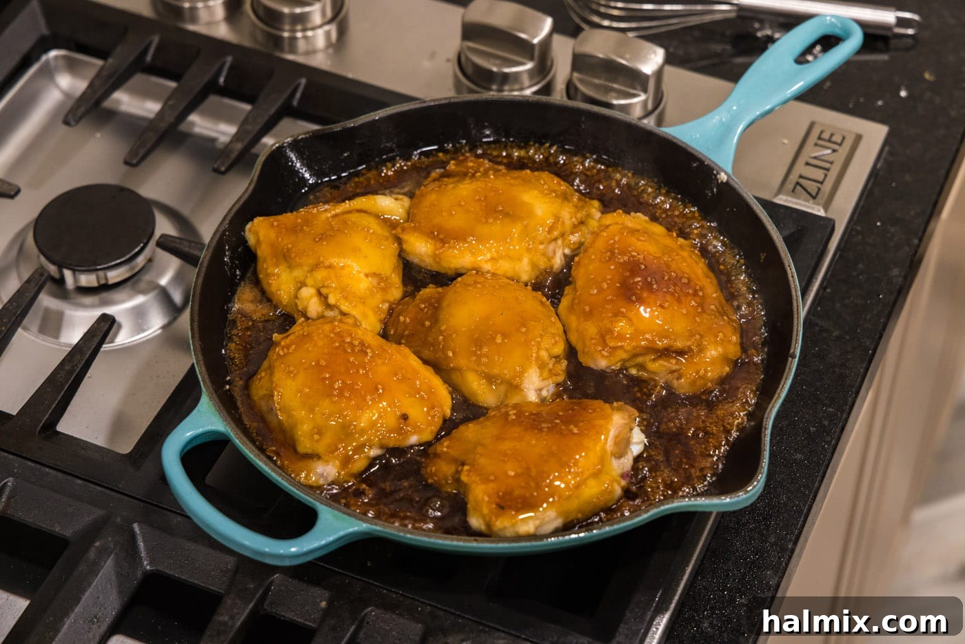 chicken thighs cooking in a skillet with honey garlic sauce
