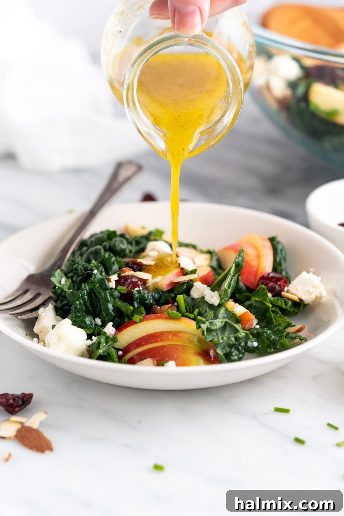 Fresh lemon dressing being drizzled over a bowl of Kale Salad